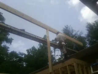 Carpenter setting a ridge beam over a new addition frame — Ice Dam Removal by Roofing Brothers in Laurel